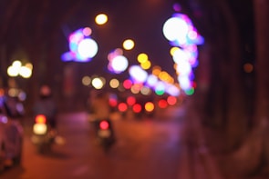 Blurred city lights coming into sharp focus through a camera lens.