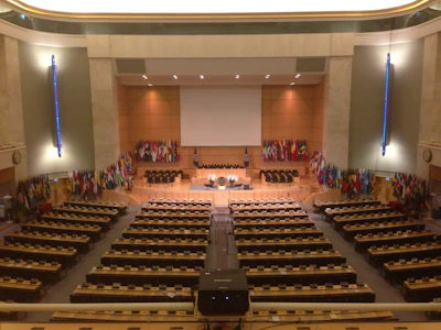 A diverse group of global leaders collaborating in a modern conference room with flags representing various nations.