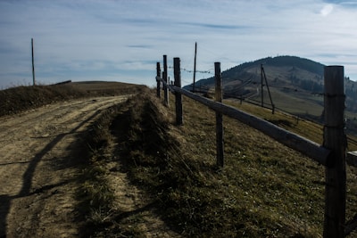 Close-up of hands securing a sturdy cattle guard on a rural dirt road surrounded by brush.