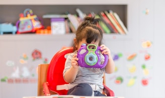 girl holding purple and green camera toy