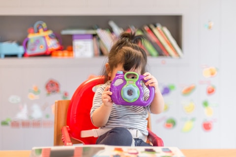 girl holding purple and green camera toy