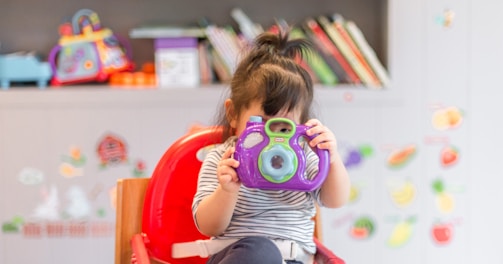 girl holding purple and green camera toy