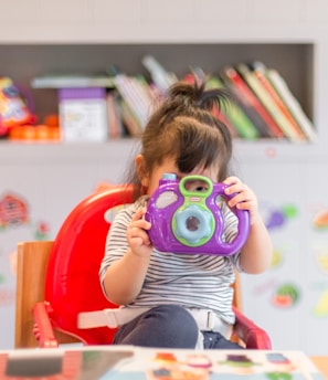 girl holding purple and green camera toy