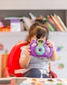 girl holding purple and green camera toy