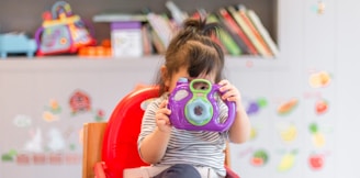 girl holding purple and green camera toy