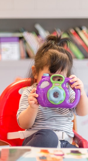 girl holding purple and green camera toy