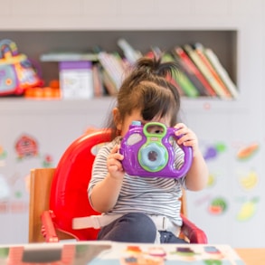 girl holding purple and green camera toy