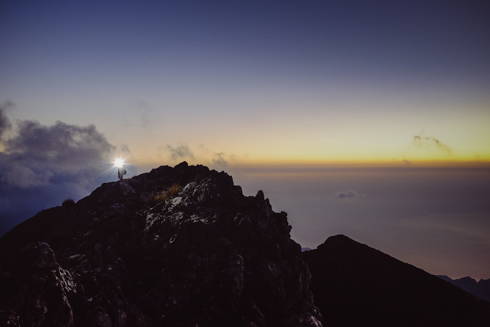 Persona in piedi sulla formazione rocciosa sotto il cielo blu durante il giorno