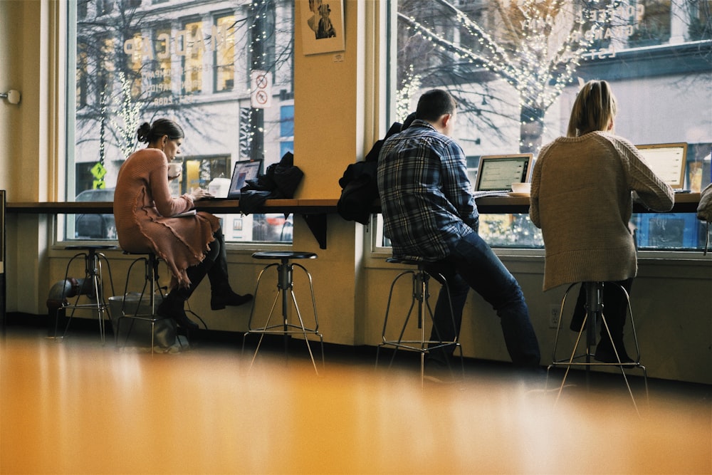 three persons sitting on bar stools