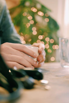 Healthy hands holding a warm cup of herbal infusion with blurred green garden background.