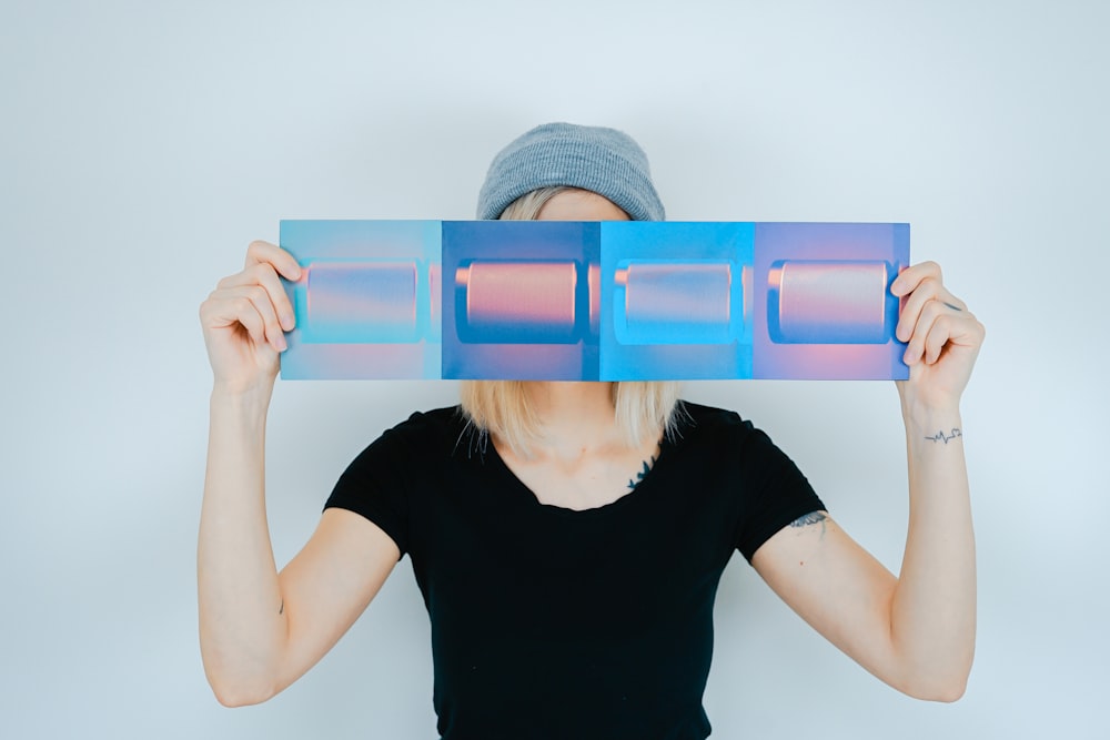 person holding blue paper covering her face