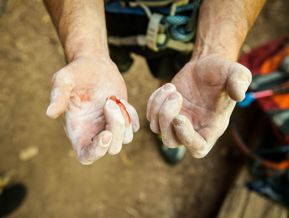 a man holding out his hands covered in mud