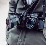person with two black DSLR cameras