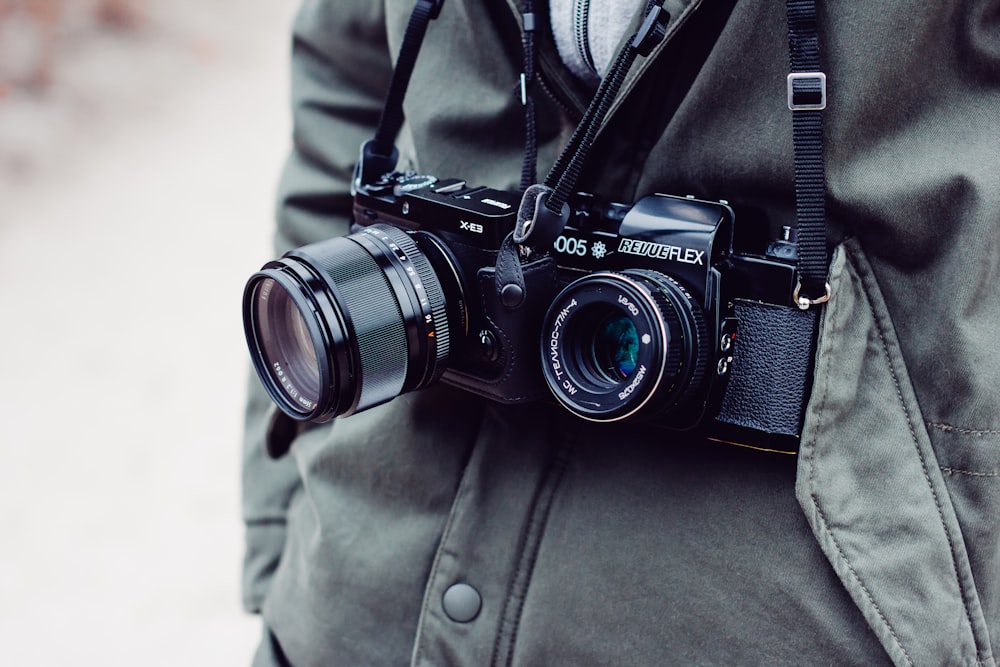 person with two black DSLR cameras