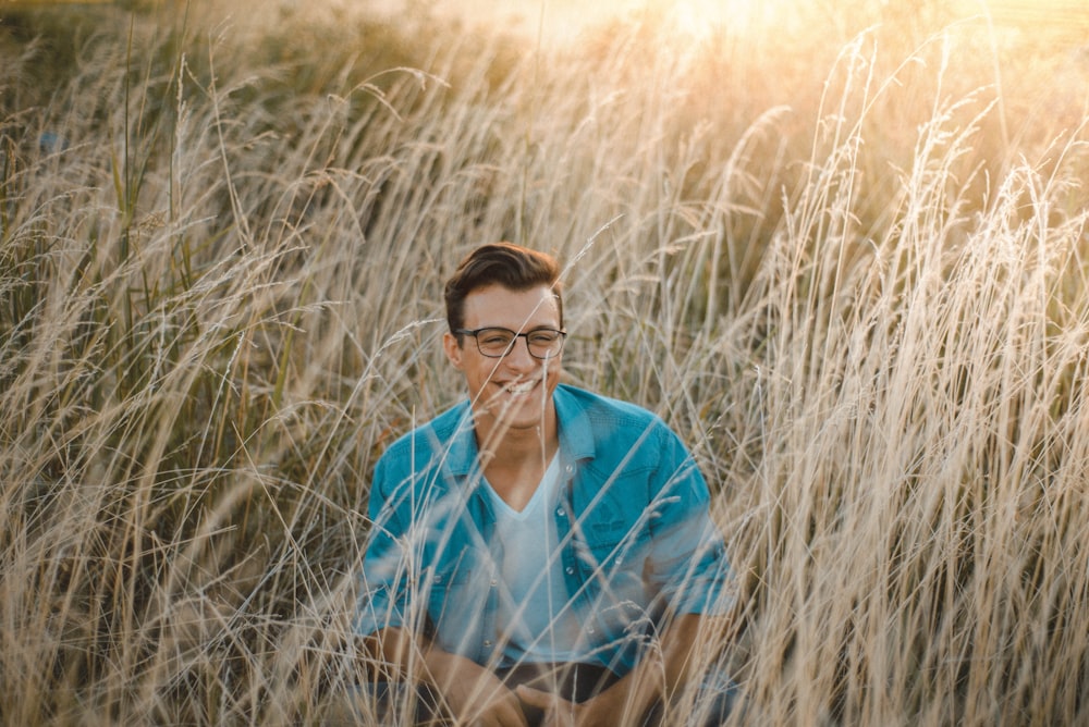 man sitting surrounded by grass during daytime