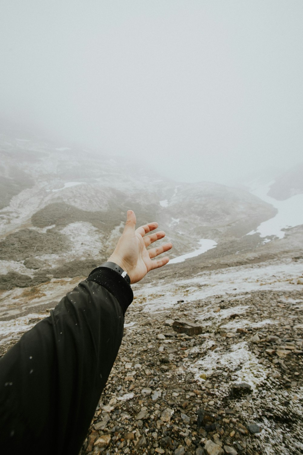 persona levantando la mano y mirando hacia la montaña
