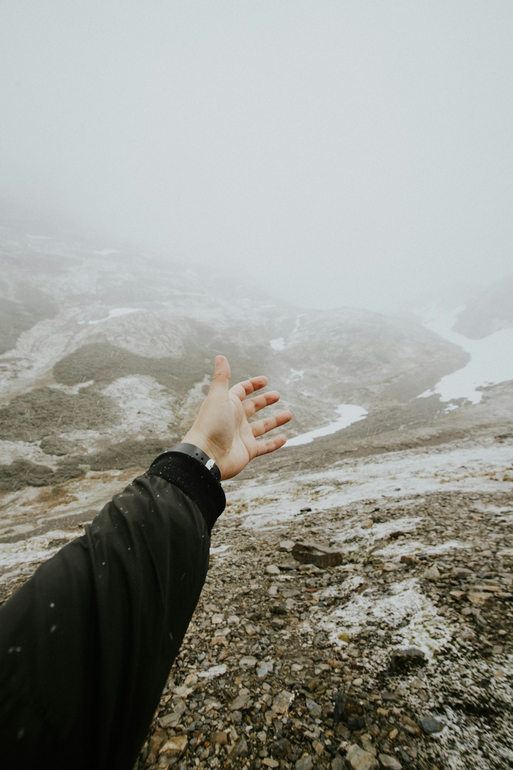 persona che alza la mano e si rivolge alla montagna