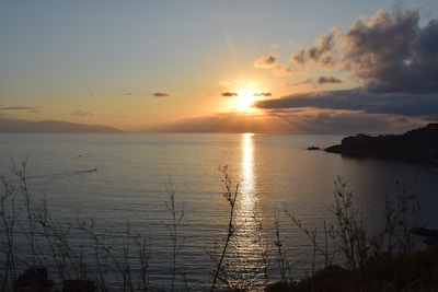 A serene seascape photograph capturing the golden light of sunset over calm waters.