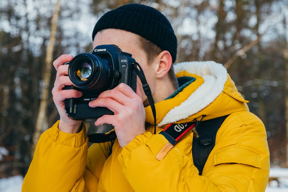 homme utilisant un appareil photo reflex numérique Canon noir pendant la journée