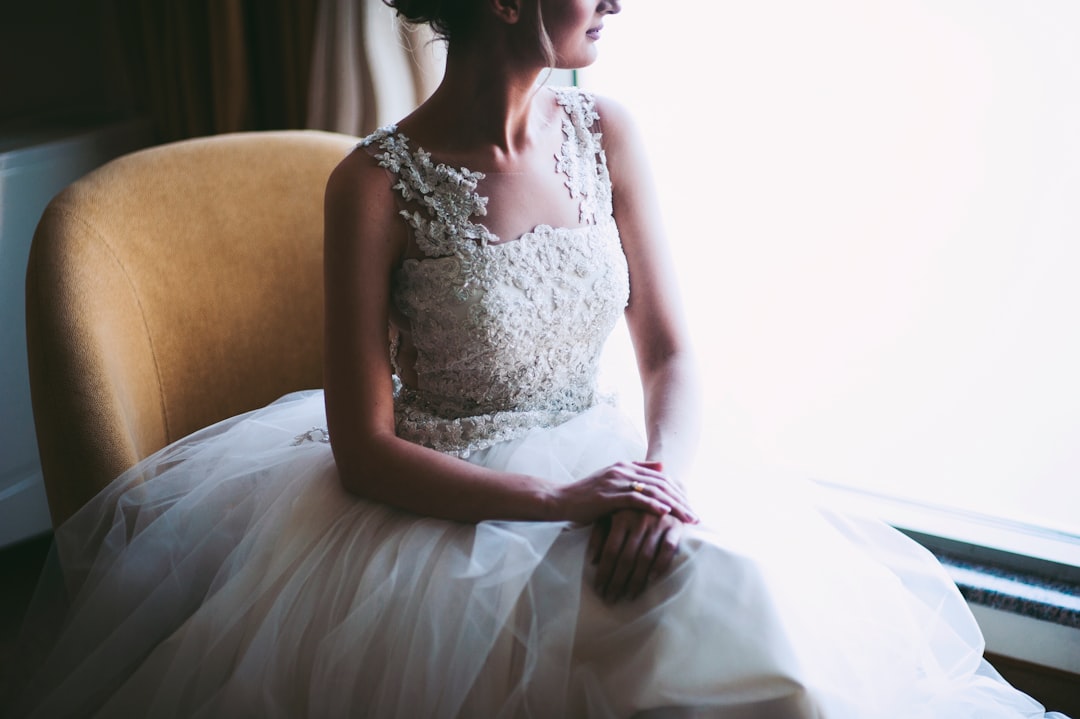 woman in white wedding dress sitting near window