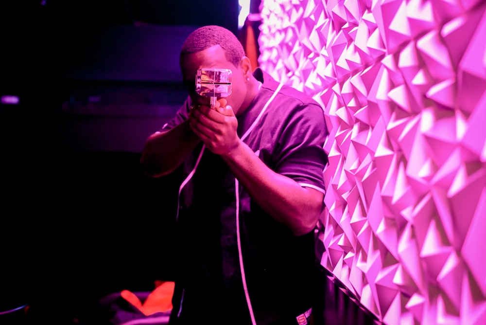 shallow focus photography of man holding camera beside pink LED light