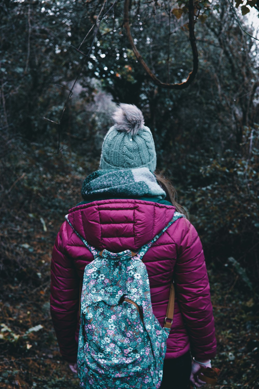 person walking between green trees