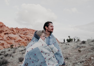 man and woman covered in blue blanket