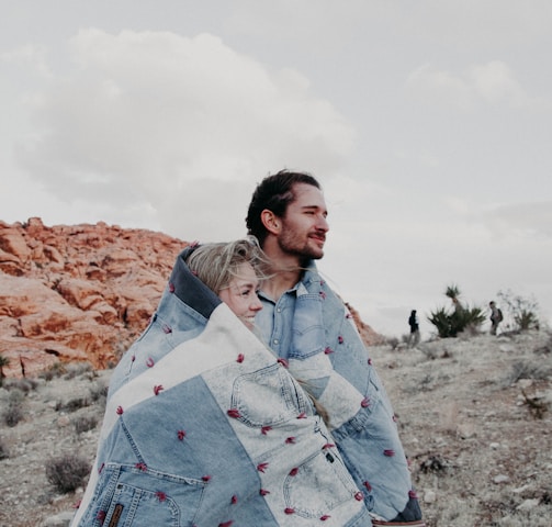 man and woman covered in blue blanket