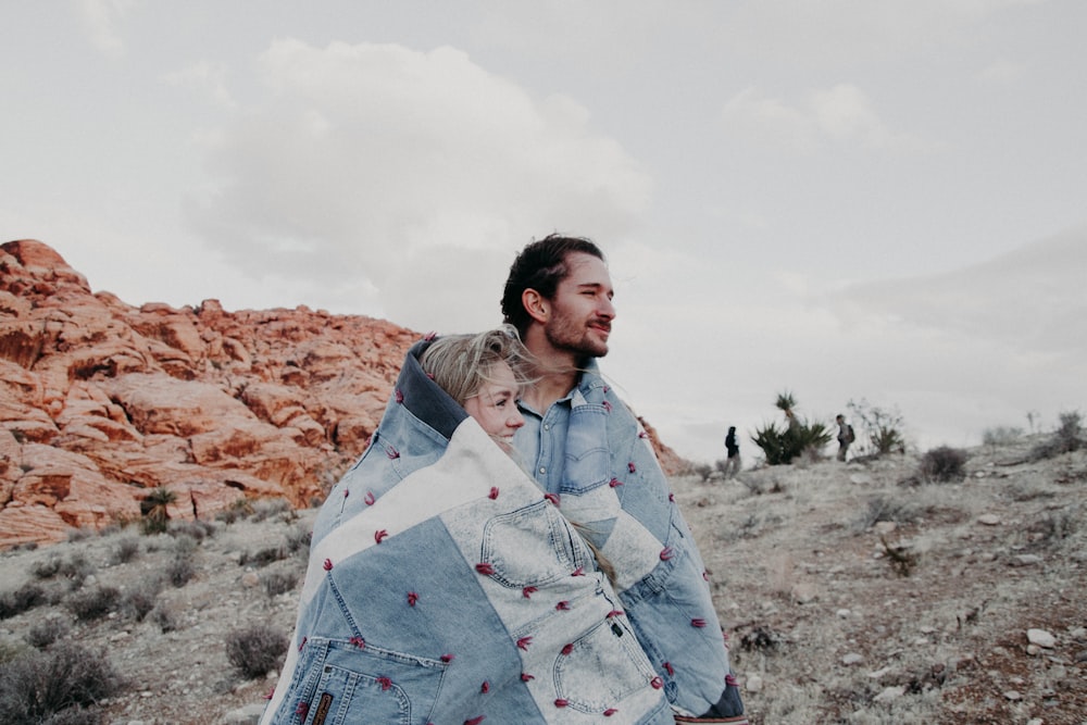 man and woman covered in blue blanket