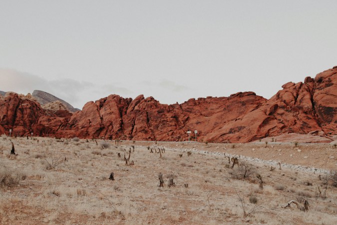 Red sandstone rock formations rising above dry desert land, the kind of scenery that draws buyers to Summerlin's western edge
