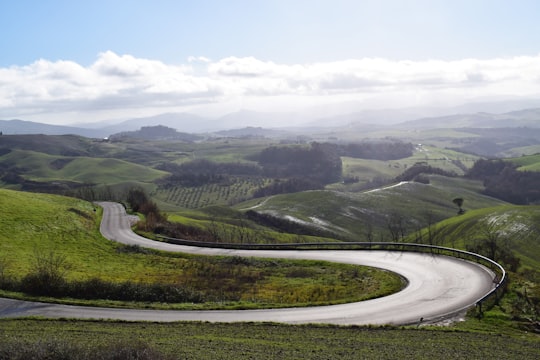 green grass field under white clouds during daytime in Volterra Italy