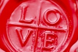 A close-up view of a red wax seal with the word 'LOVE' embossed in the center, divided into quadrants by lines.