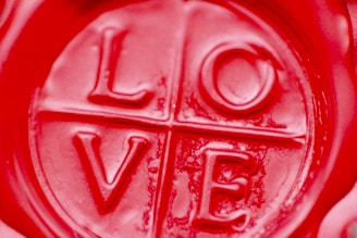 A close-up view of a red wax seal with the word 'LOVE' embossed in the center, divided into quadrants by lines.