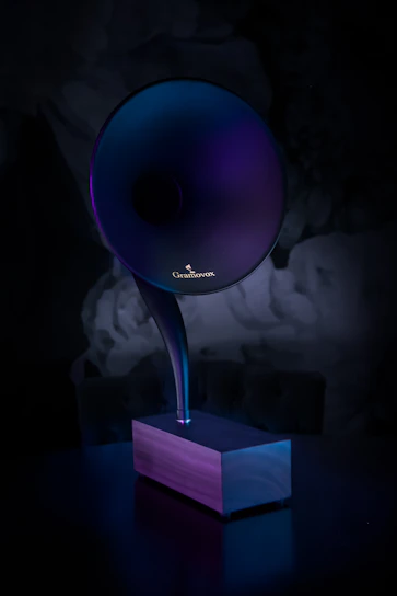 A sleek twilight-themed Bluetooth speaker glowing softly on a wooden table at dusk.