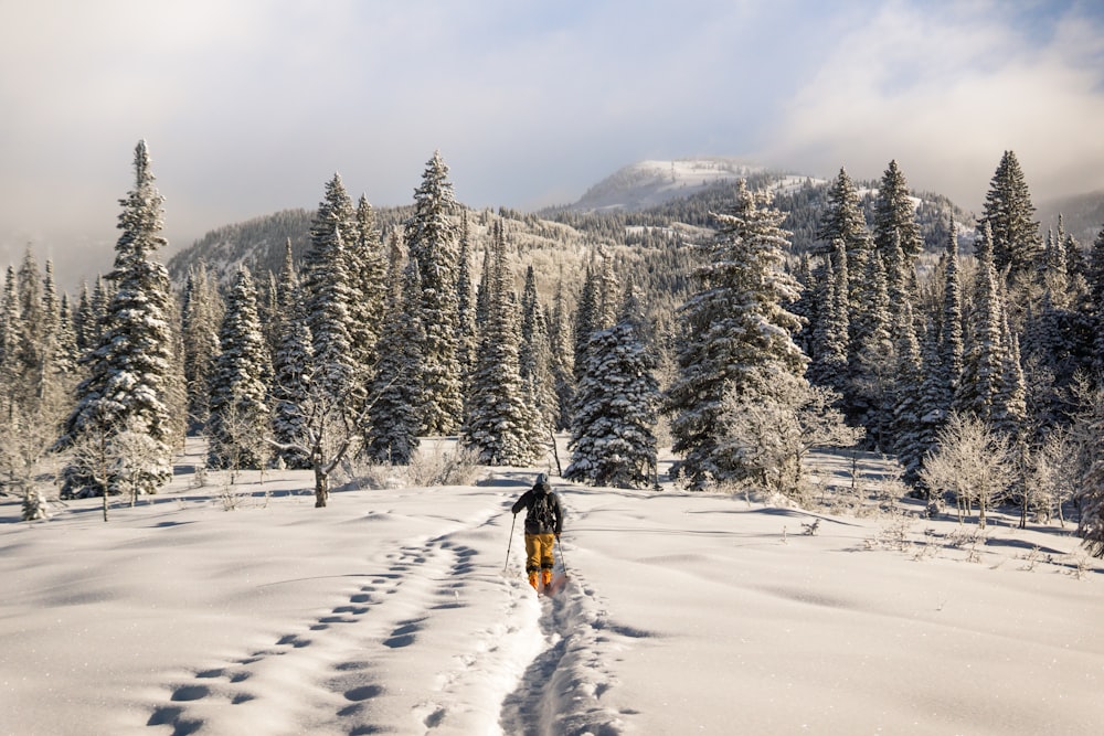 Hombre con traje negro y naranja caminando sobre la nieve