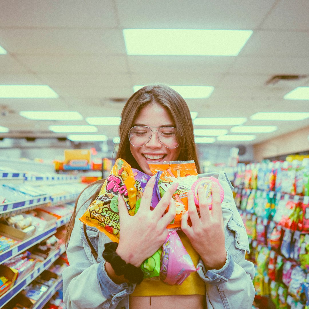 foto engraçada de menina sorrindo com várias comidas doces na mão 