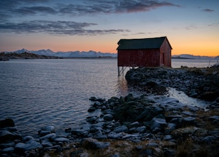 red and green house with body of water under blue sky during daytime