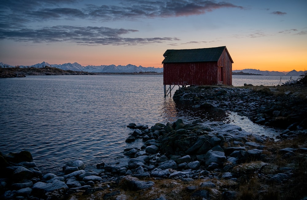 red and green house with body of water under blue sky during daytime