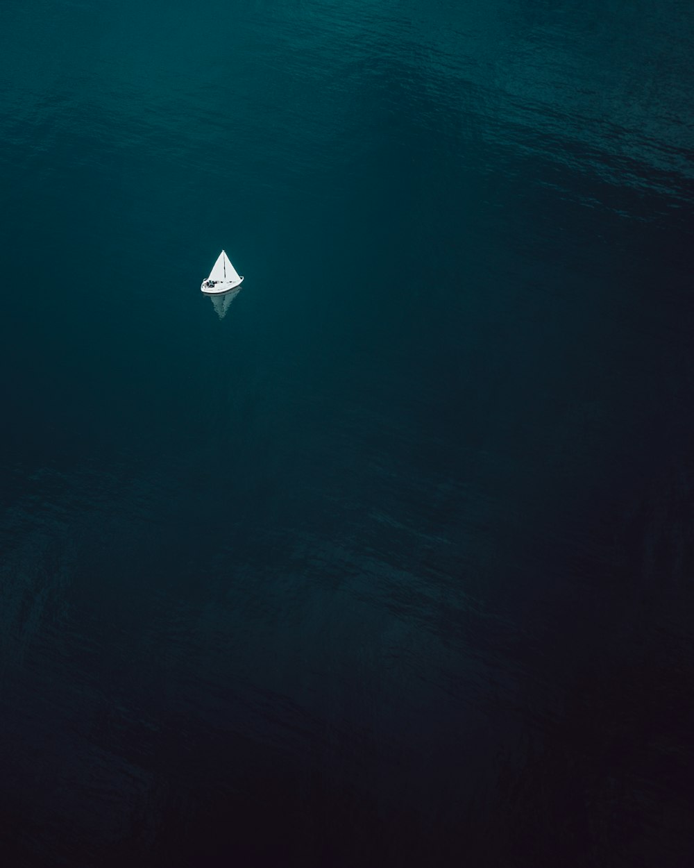 fotografia aerea di una barca a vela che naviga su uno specchio d'acqua
