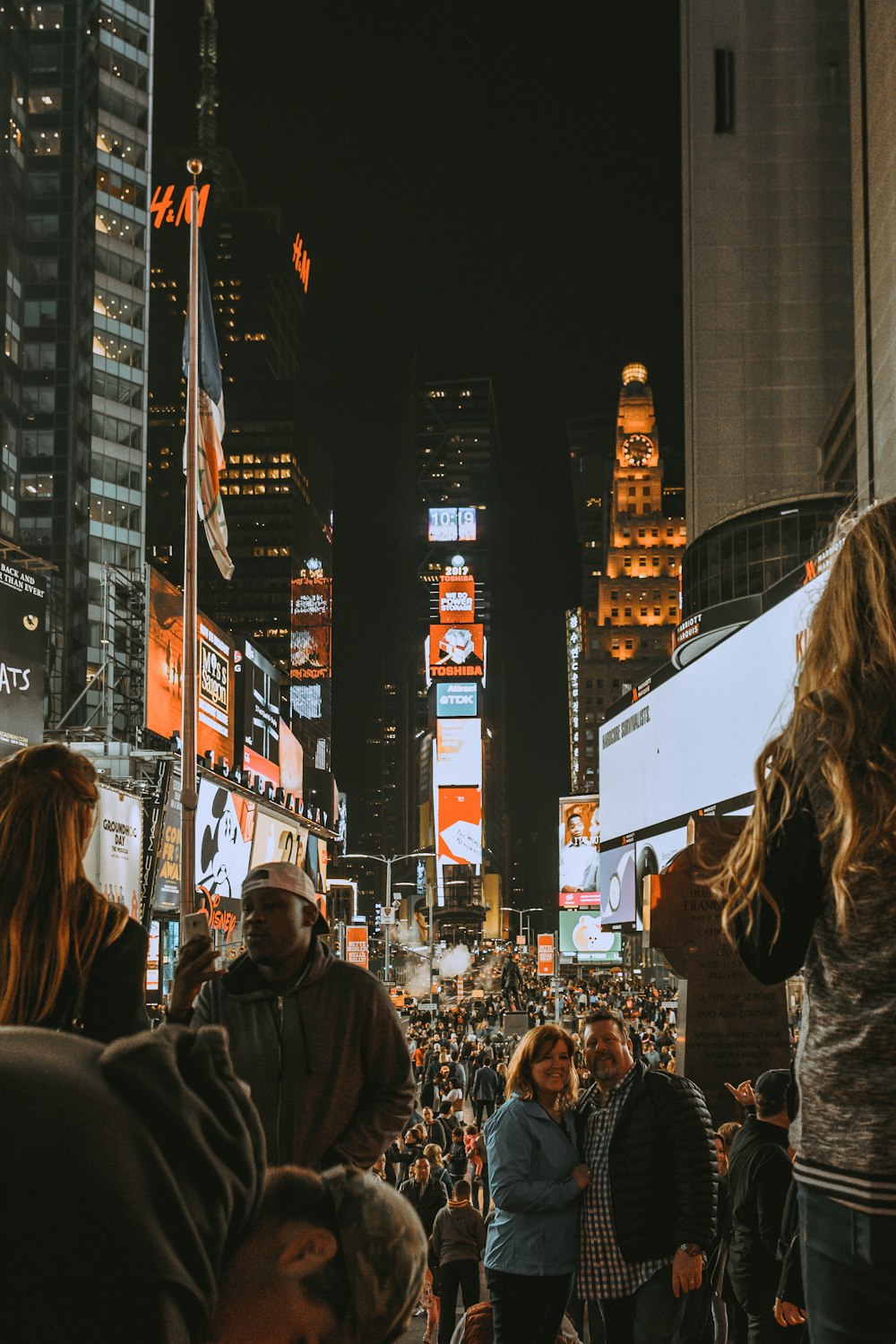 Homem e mulher em pé tirando fotos atrás de prédios de andares