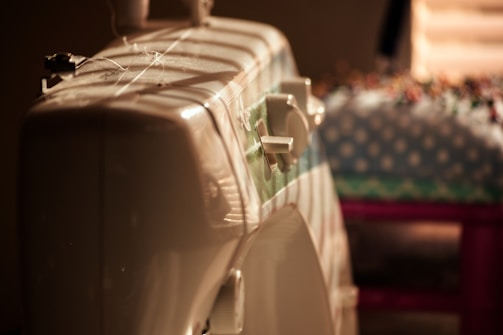 Warm photo of a sewing machine with fabric and threads in a cozy tailoring workshop.