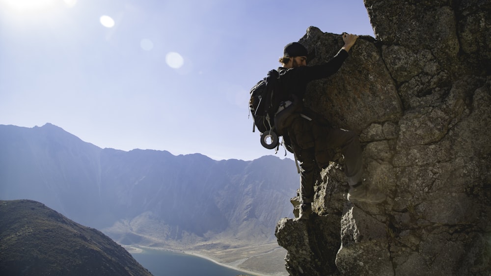 man climbing rock formation during daytime