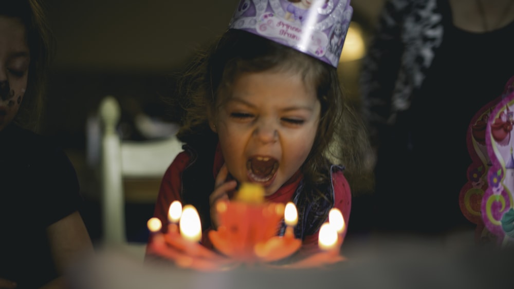 ケーキのろうそくを吹く幼児の浅い焦点の写真