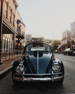 A classic vintage Volkswagen Beetle parked on a cobblestone street during sunset