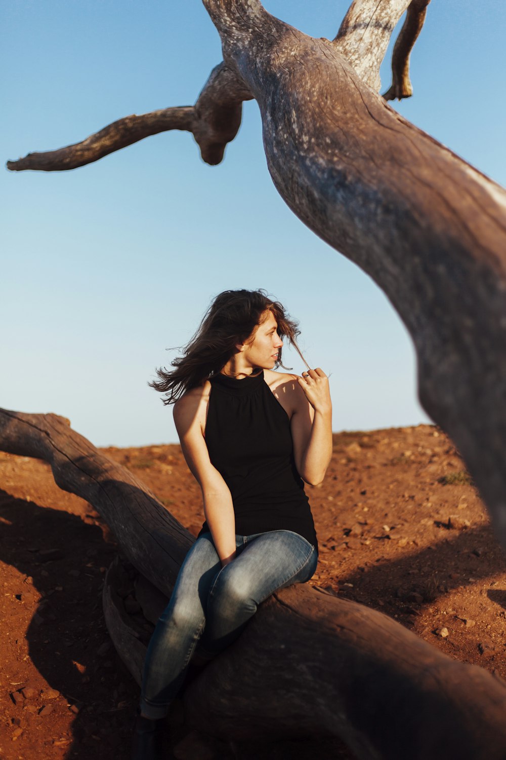 una donna seduta su un ramo dell'albero che fuma una sigaretta