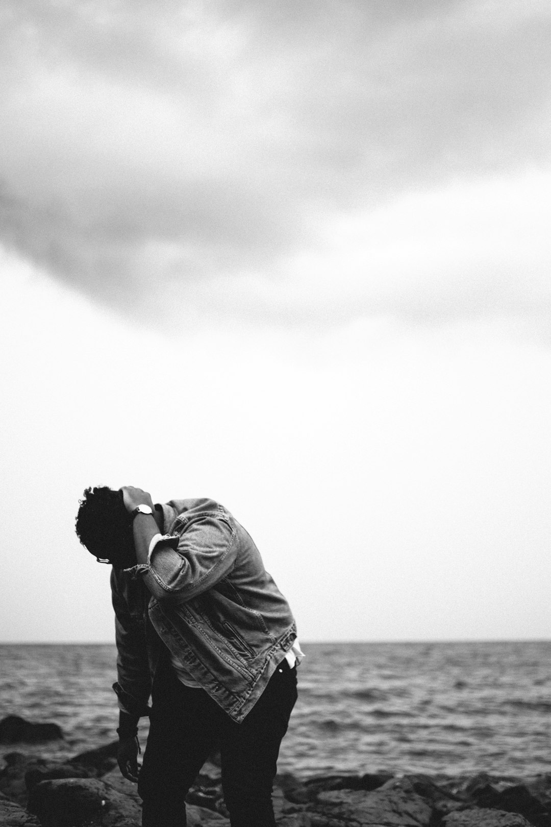 grayscale photography of person looking down at rocks