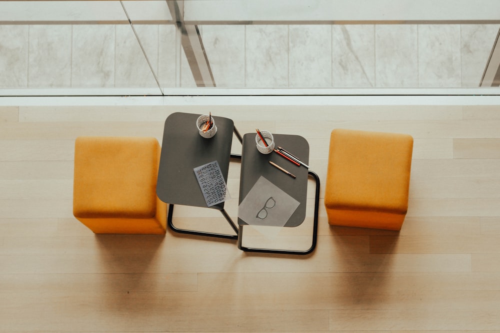 two orange ottoman chairs near gray side tables