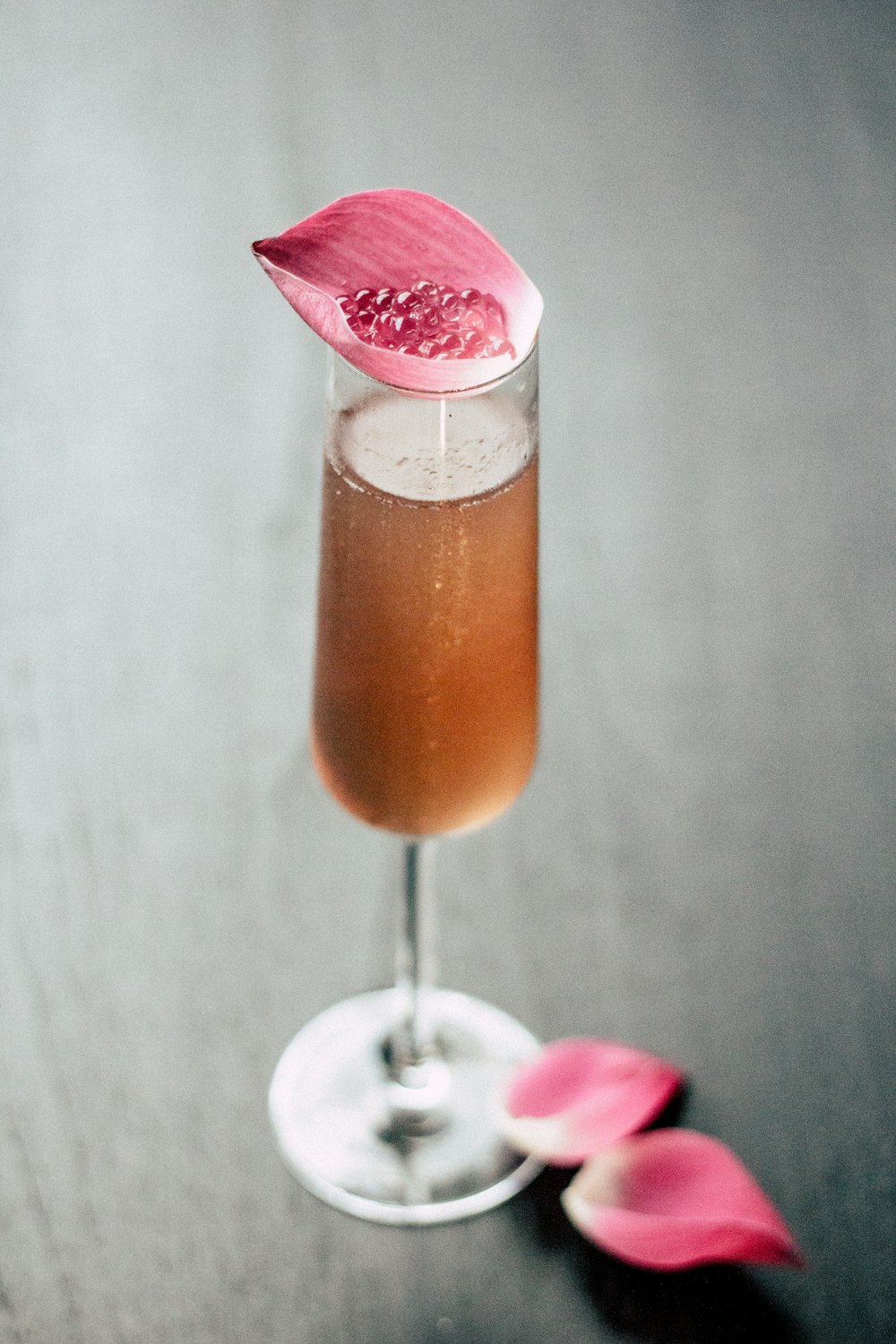 beverage in glass with pink leaf on top