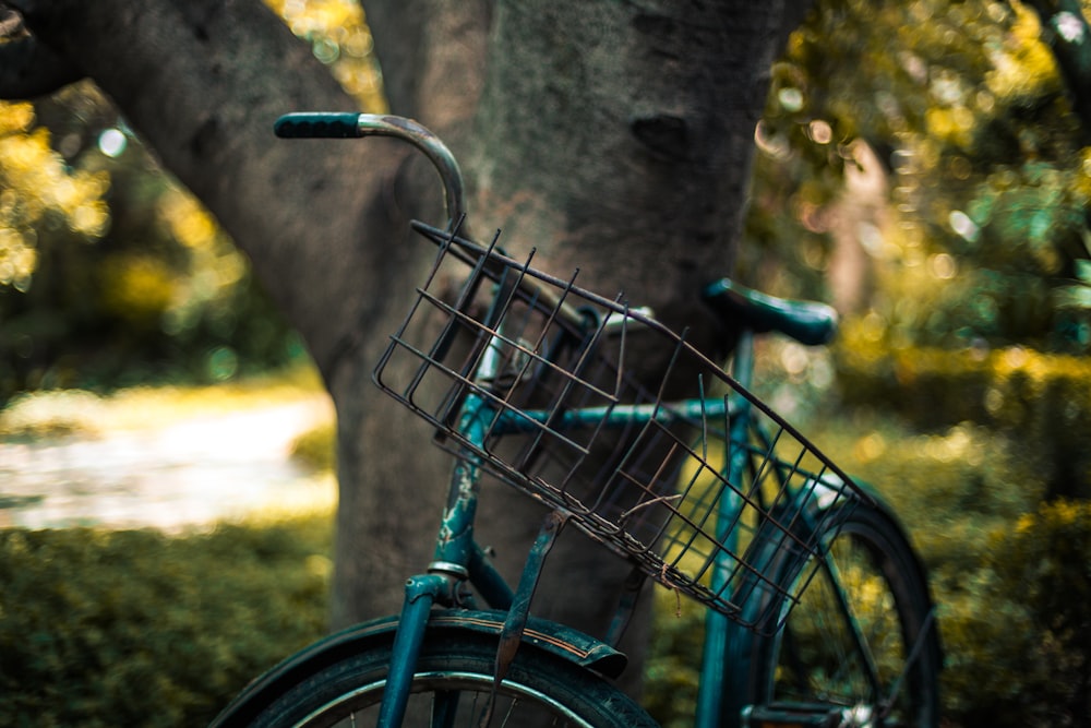 selective focus photography of blue bike parked beside tree