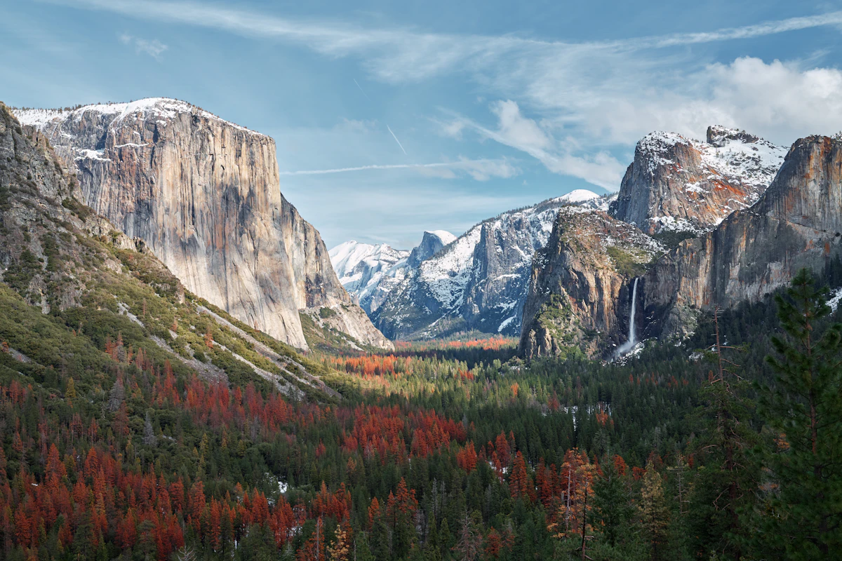 Yosemite Vadisi'nde karlı granit kayalıklar, şelale ve çam ormanı